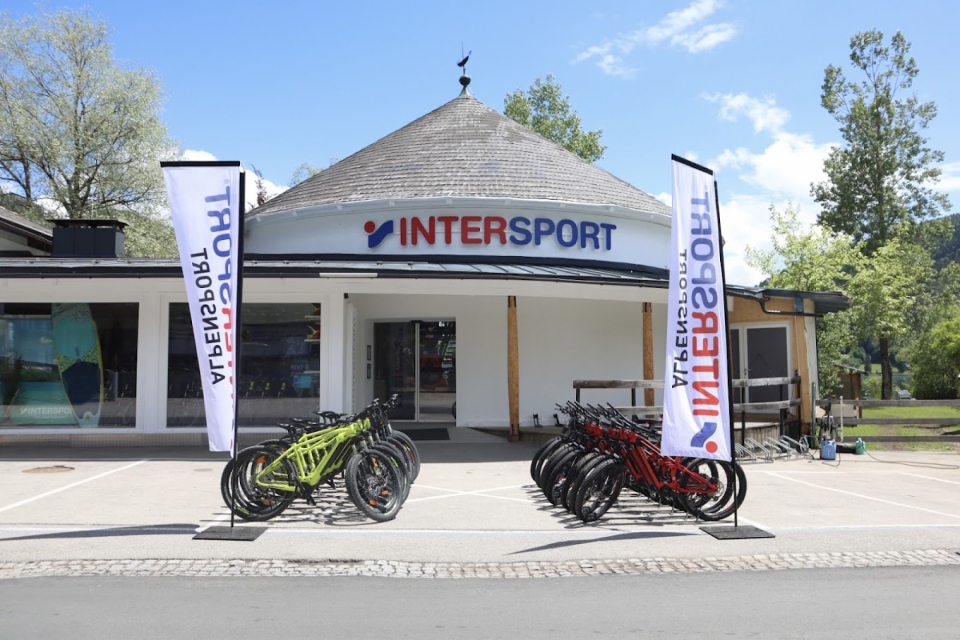 Außenansicht des Intersport-Geschäfts mit vor dem Laden geparkten Leihfahrrädern in Zell am See, Österreich.