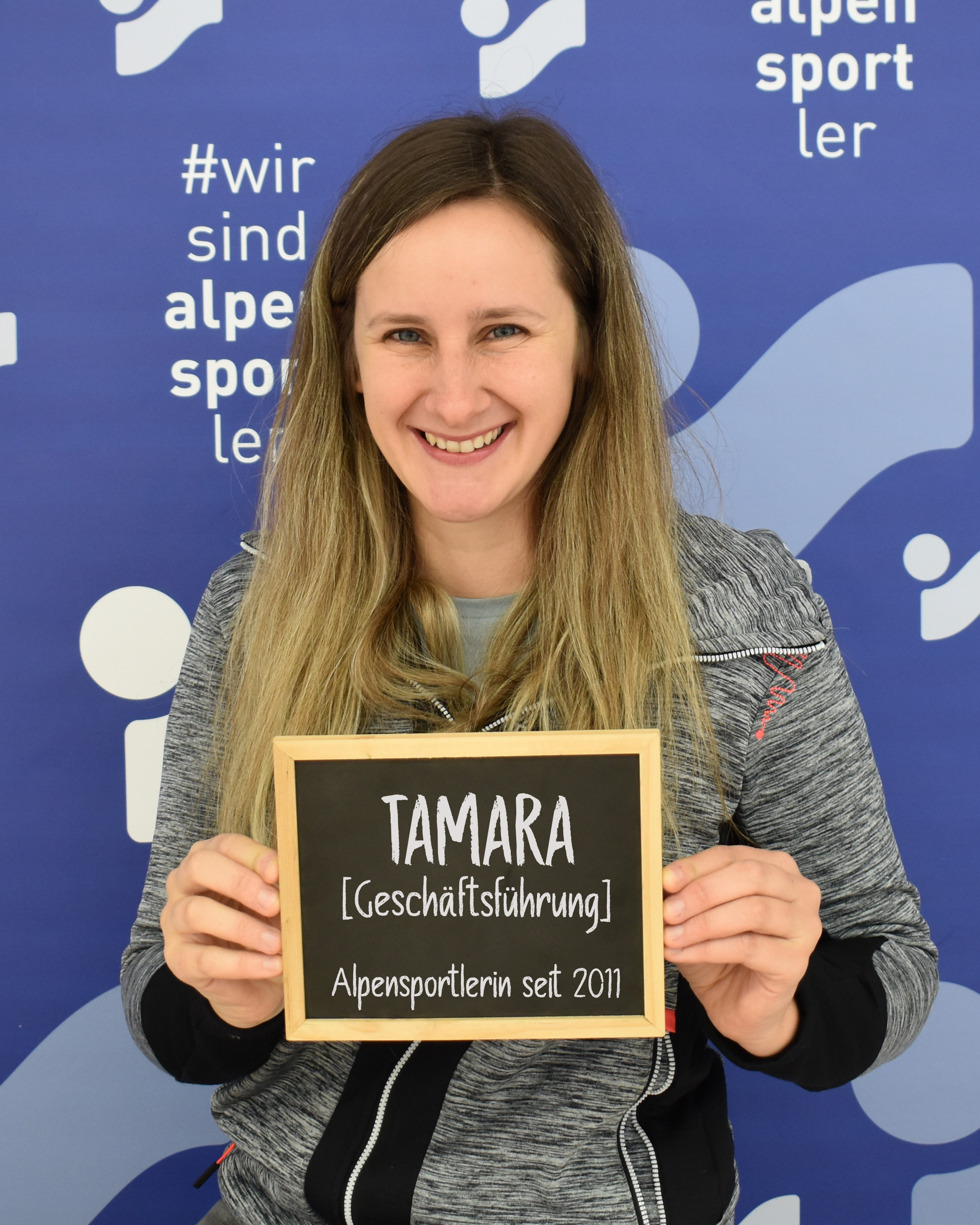 Lächelnde Frau hält Schild: Tamara, Alpensportlerin seit 2011