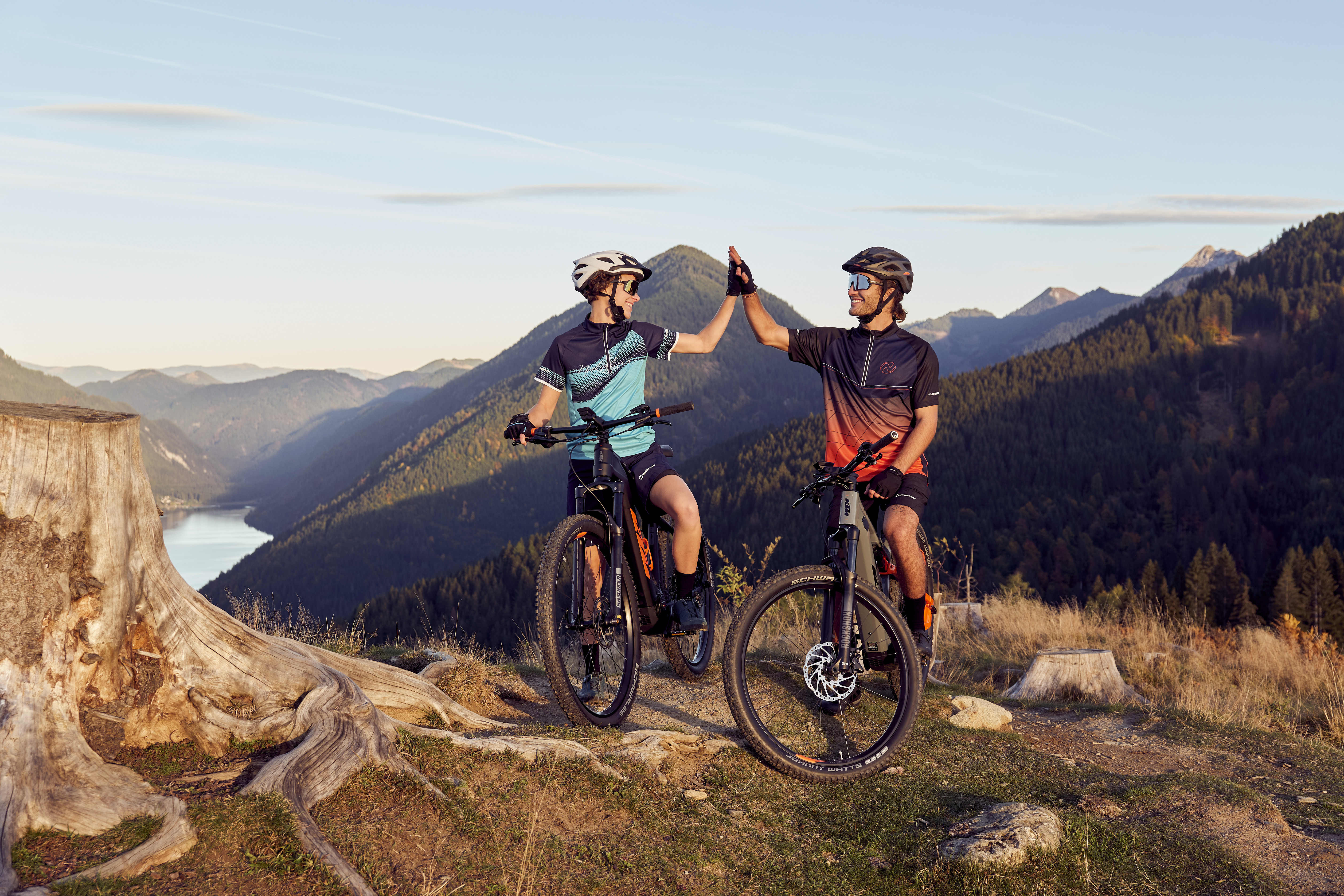Zwei Mountainbiker, die sich auf einem Trail mit malerischer Bergkulisse abklatschen.
