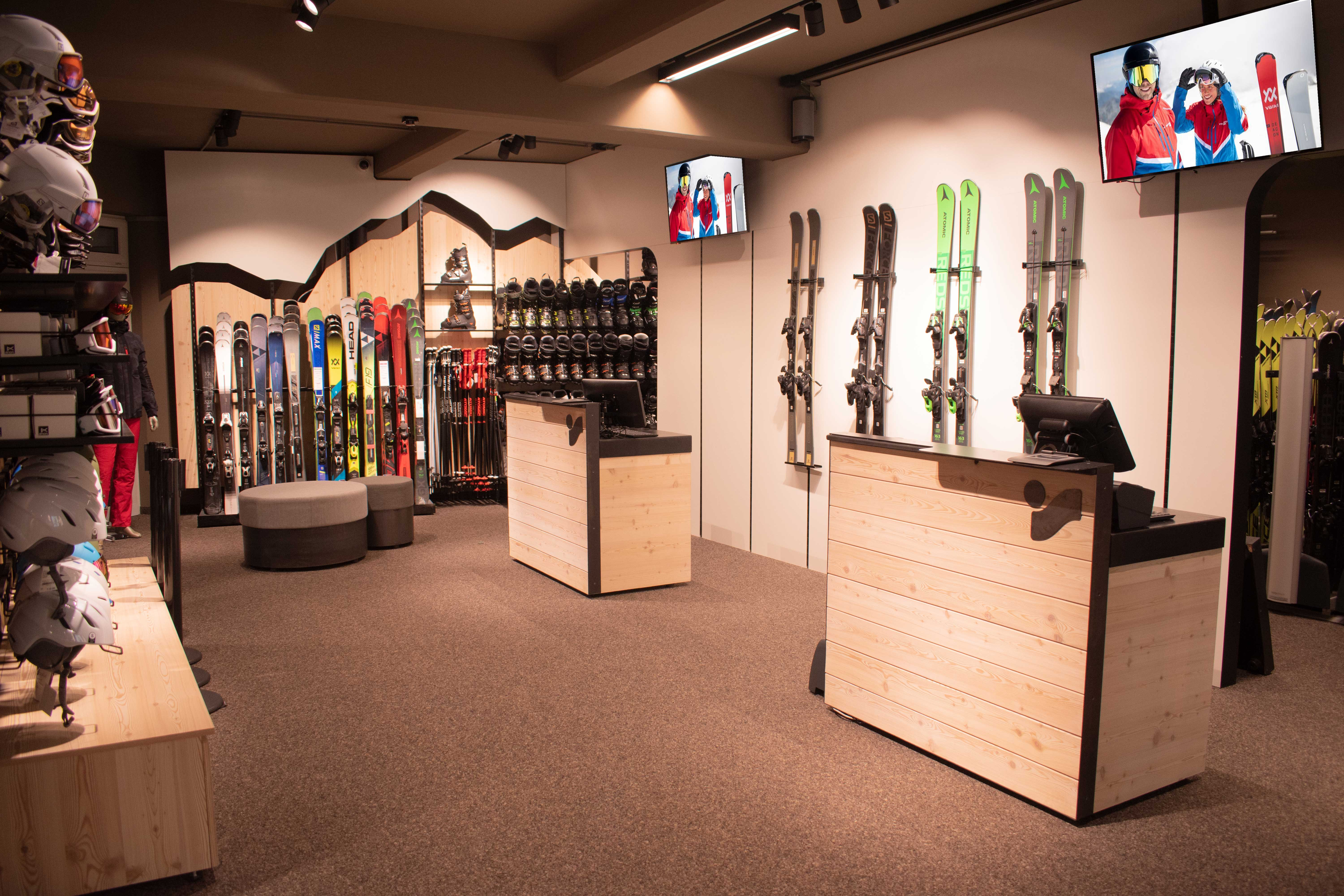 Innenausstattung eines Skigeschäfts mit Skiern, Snowboards, Helmen und Kassentischen für den Verkauf von Wintersportausrüstung.