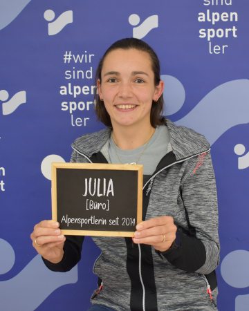 Lächelnde Julia hält ein Schild für Alpensportler