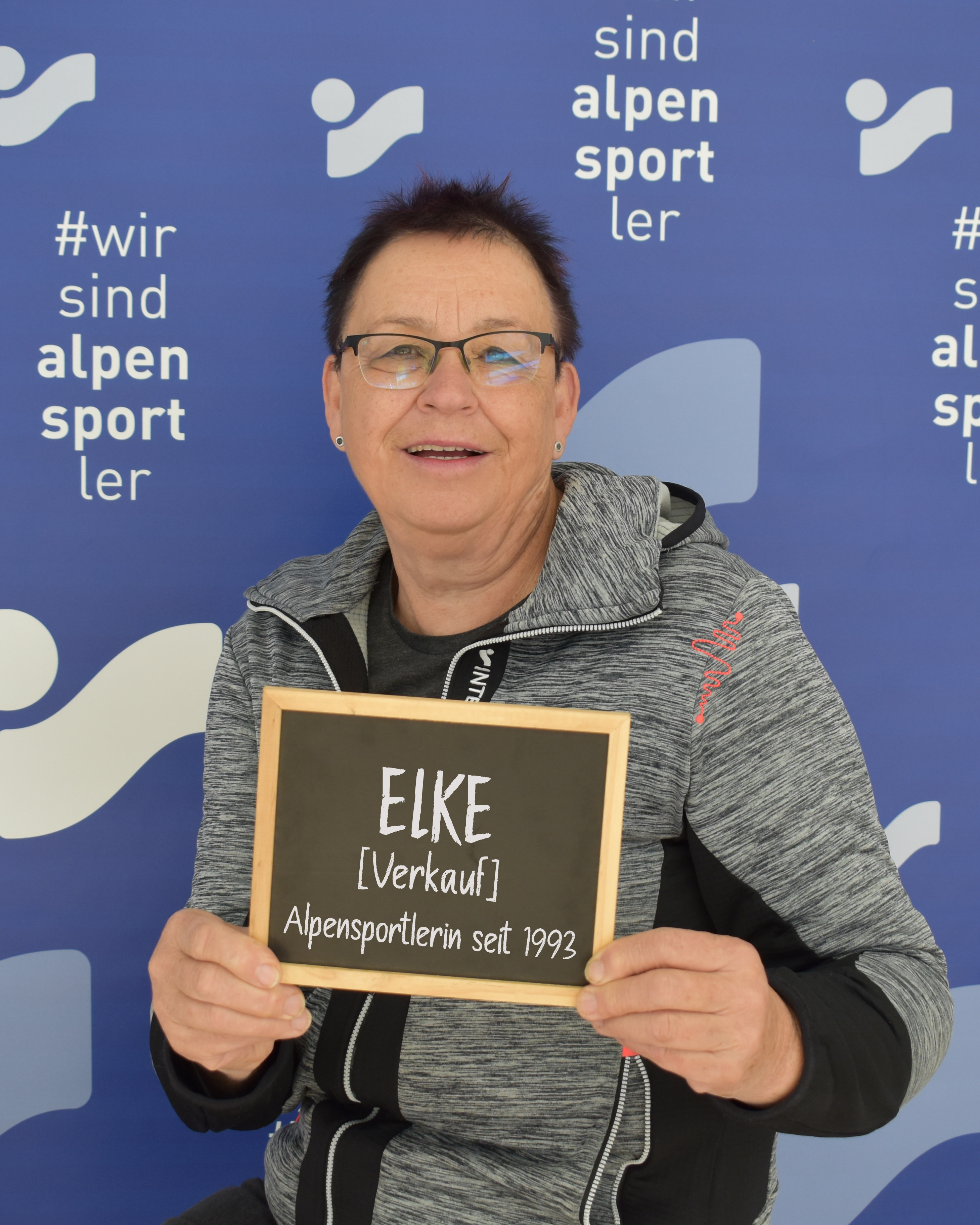 Frau hält "ELKE [Verkauf]" Schild für Alpensport.