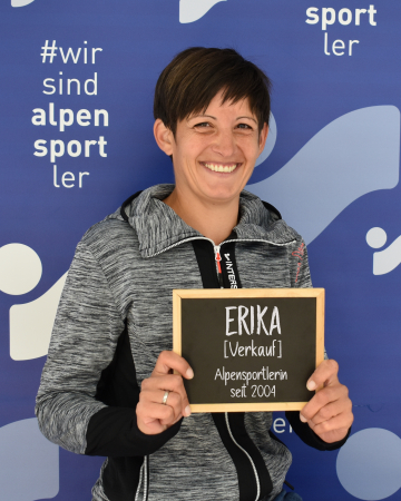 Die lächelnde Erika, Alpensportlerin seit 2004, hält ein Schild.