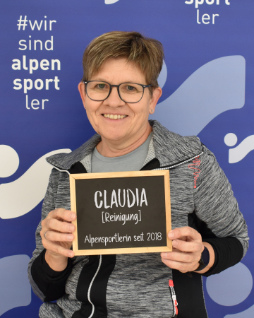 Lächelnde Frau hält ein Schild: Claudia, Reinigungsservice, Alpensportlerin seit 2018.