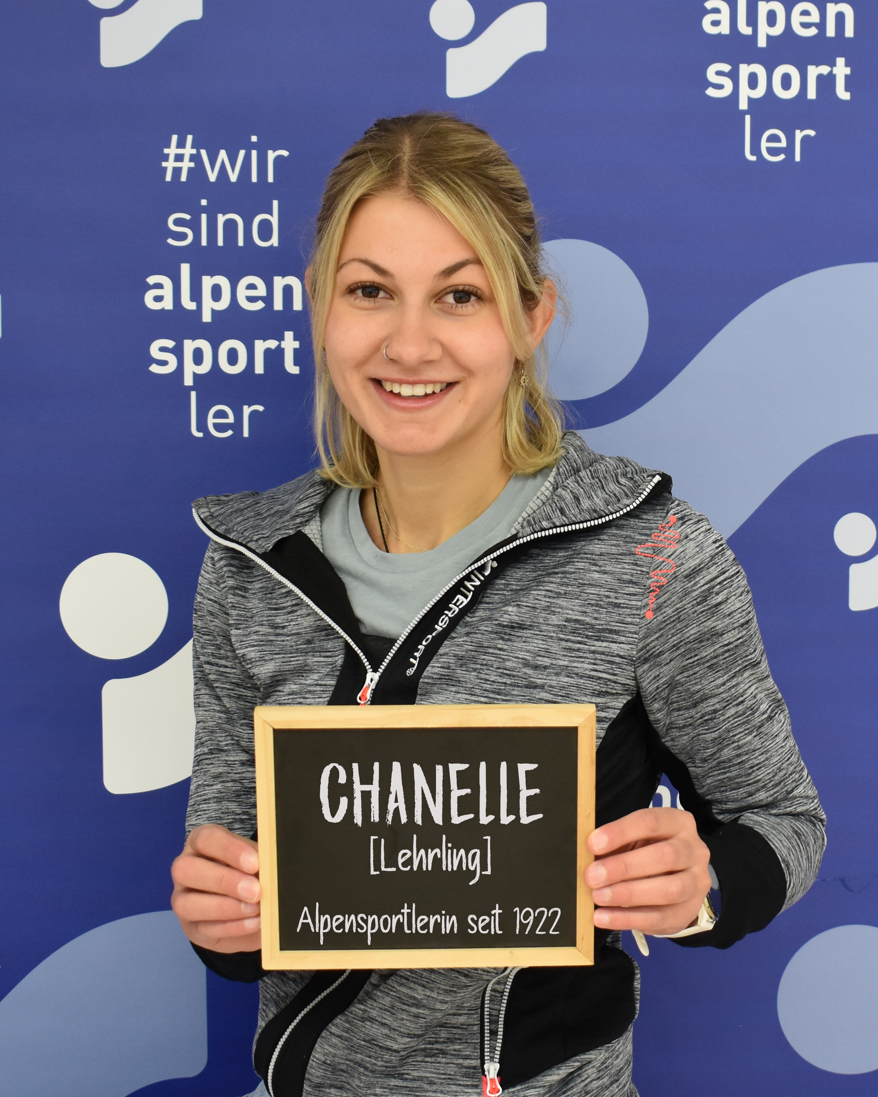 Chanelle, Alpensport athlete, holding sign with name; Alpen sports promotion, ski and outdoor sports.