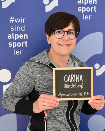 Carina hält ein Schild mit Namen und Titel.