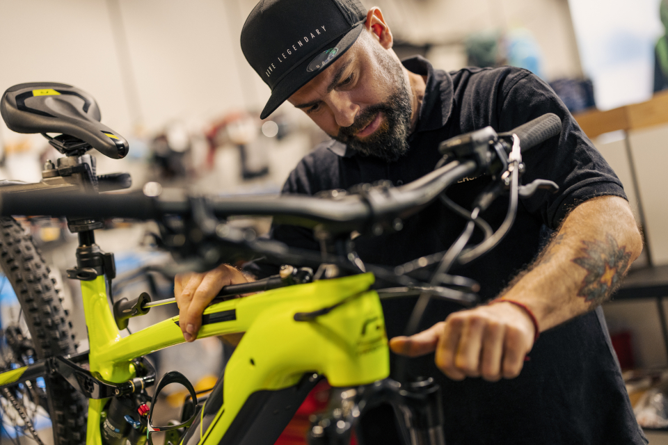 Fahrradmechaniker repariert ein neongrünes Mountainbike in einer Werkstatt; Fahrradwartung und -service.