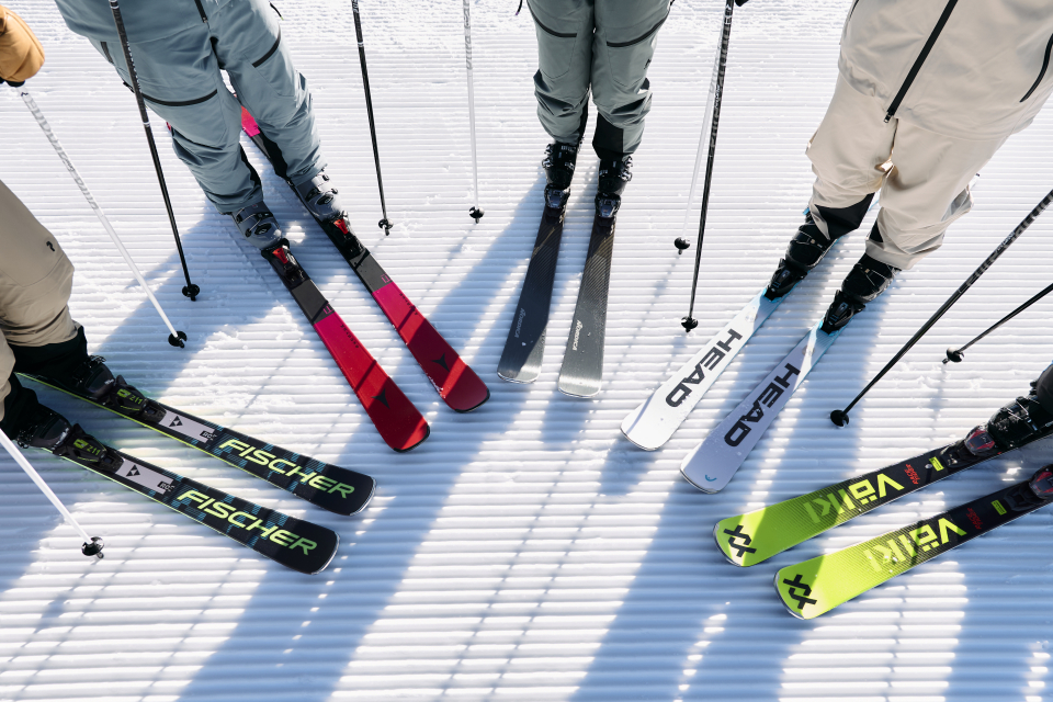 Blick von oben auf Skifahrer mit Skiern der Marken Fischer, Head und Volkl auf einer präparierten Skipiste.