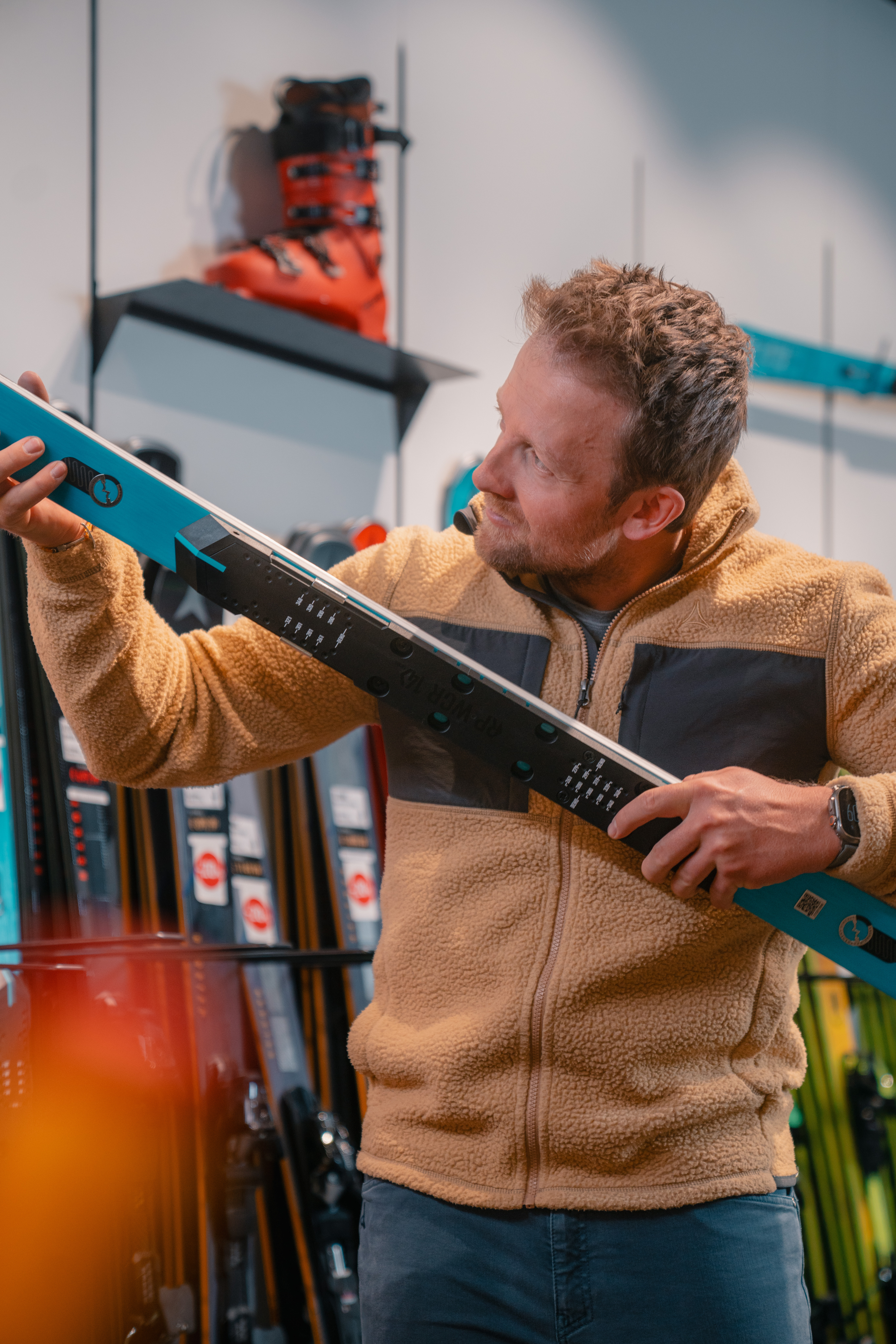 Mann begutachtet neue Skier in einem Skigeschäft; Kauf von Wintersportausrüstung.